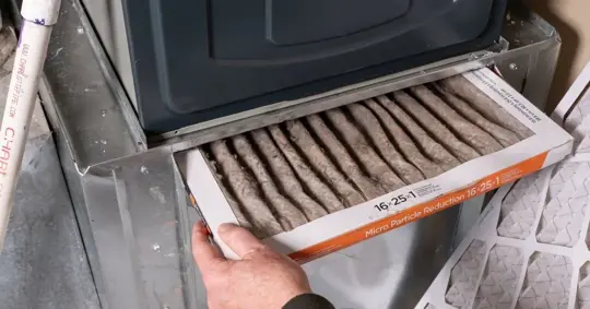 Man replacing dirty furnace filter at home